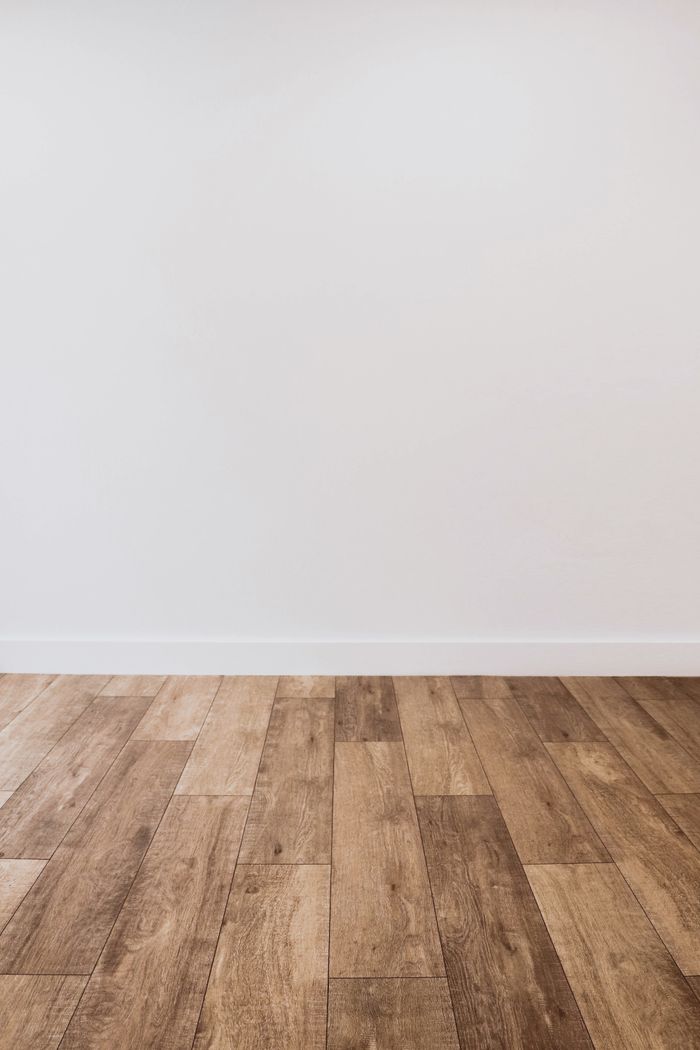 Clean white wall with wooden flooring offering versatile copy space.